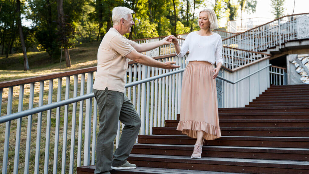 personnes agees se tenant la main dans un escalier pour eviter les causes de chutes avec bip connect